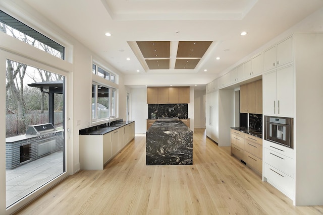 kitchen featuring tasteful backsplash, oven, light wood-style floors, a sink, and recessed lighting