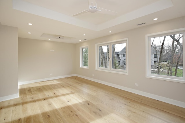 unfurnished room with ceiling fan, a raised ceiling, and light hardwood / wood-style flooring