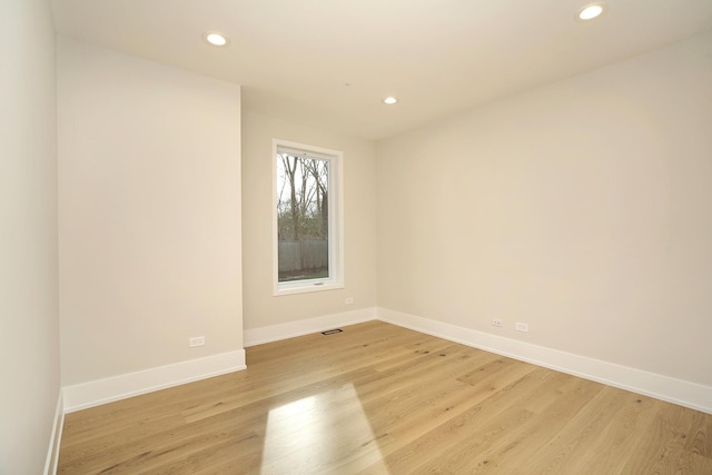 empty room featuring baseboards, light wood-type flooring, visible vents, and recessed lighting