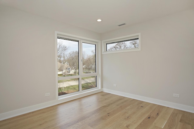 empty room with light wood-type flooring, plenty of natural light, visible vents, and baseboards