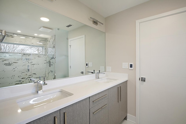 full bathroom with double vanity, a marble finish shower, visible vents, and a sink