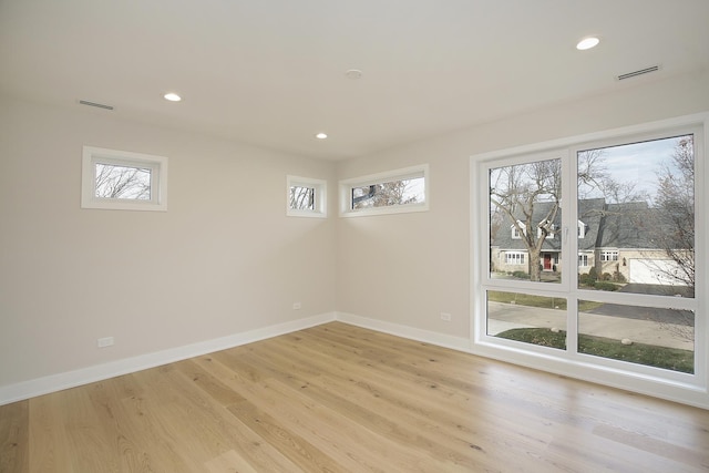 empty room featuring a wealth of natural light, light wood-type flooring, and baseboards