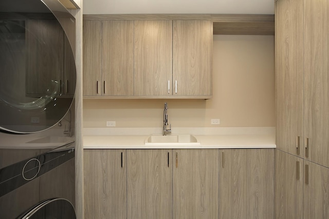 clothes washing area featuring stacked washing maching and dryer, a sink, and cabinet space