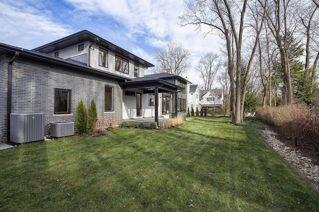 exterior space featuring a patio area, brick siding, a yard, and central AC