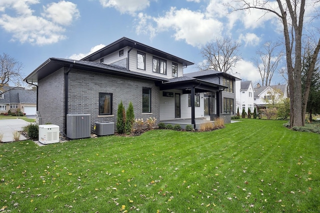 back of house featuring a patio, brick siding, a lawn, and cooling unit