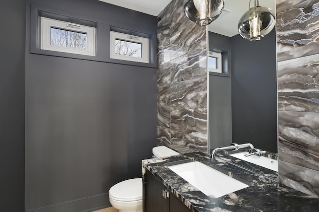 half bathroom featuring a wealth of natural light, vanity, and toilet