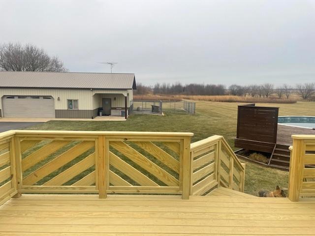 wooden deck with a yard, a rural view, and a pool