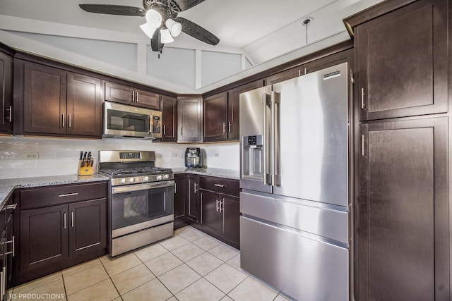 kitchen featuring vaulted ceiling, ceiling fan, light stone counters, dark brown cabinetry, and stainless steel appliances