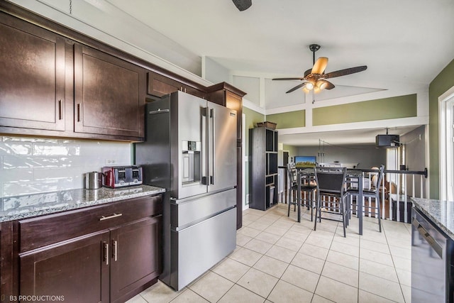 kitchen with high end refrigerator, dark brown cabinets, ceiling fan, stone countertops, and lofted ceiling