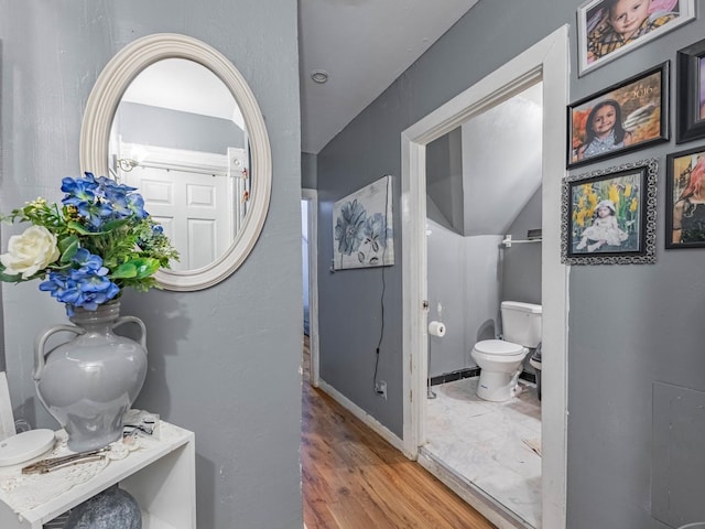 bathroom featuring hardwood / wood-style floors, toilet, and vaulted ceiling