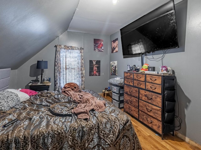 bedroom with vaulted ceiling and light hardwood / wood-style flooring