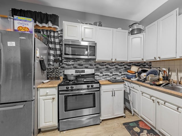 kitchen with sink, white cabinetry, backsplash, and appliances with stainless steel finishes