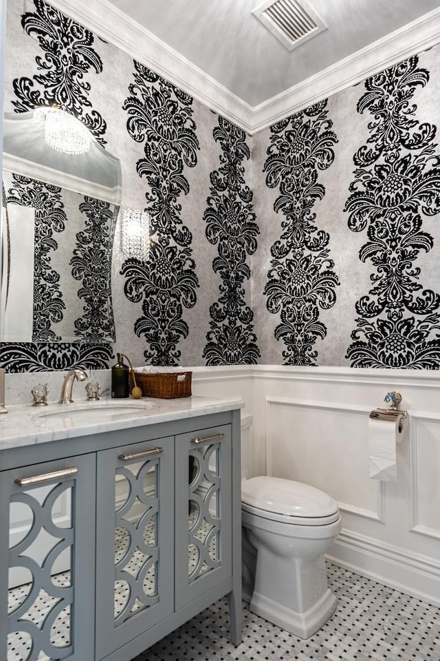 bathroom featuring toilet, vanity, and ornamental molding