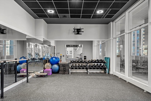 gym featuring a paneled ceiling, plenty of natural light, and a towering ceiling