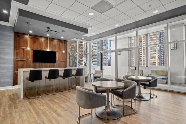 interior space with a paneled ceiling, plenty of natural light, and light hardwood / wood-style floors