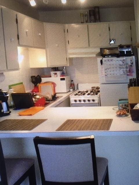 kitchen with extractor fan, tasteful backsplash, and white appliances