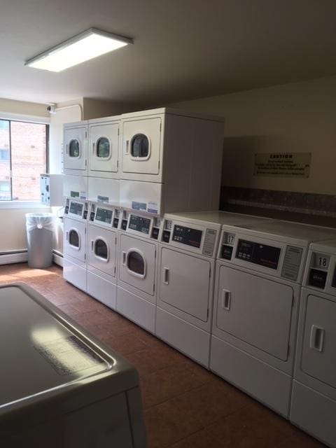 laundry room featuring stacked washer / drying machine, dark tile patterned floors, and separate washer and dryer