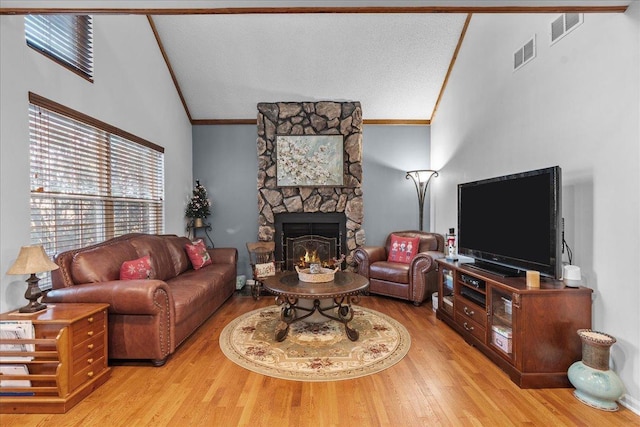 living room featuring ornamental molding, a fireplace, high vaulted ceiling, and light hardwood / wood-style flooring