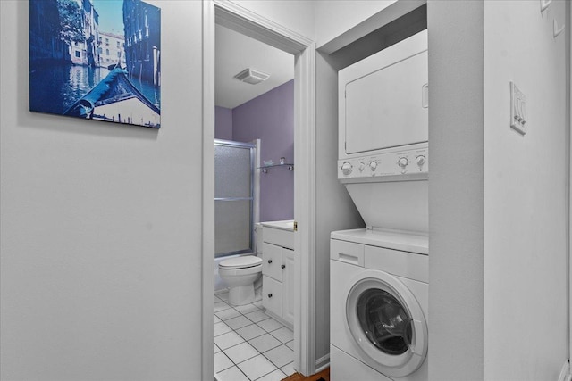 laundry room featuring light tile patterned floors and stacked washer / dryer