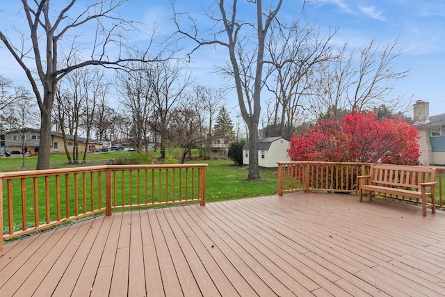 wooden terrace featuring a residential view, a lawn, and an outdoor structure