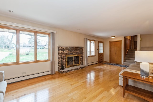 living room with a baseboard heating unit, a brick fireplace, and light hardwood / wood-style floors