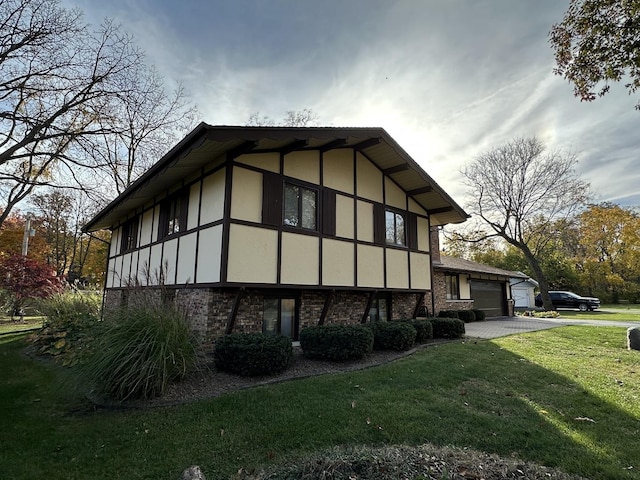 view of side of property with an attached garage, a yard, driveway, and stucco siding