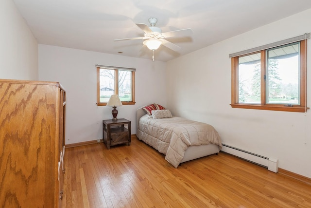 bedroom featuring a baseboard radiator, baseboards, light wood-style floors, and ceiling fan