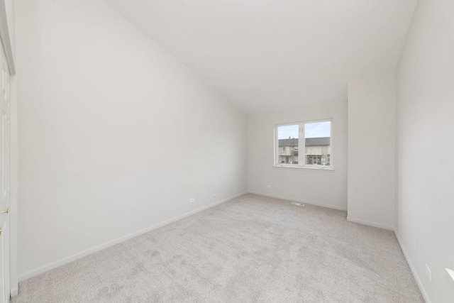 carpeted spare room featuring vaulted ceiling