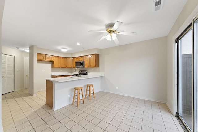 kitchen featuring ceiling fan, sink, a kitchen breakfast bar, kitchen peninsula, and light tile patterned flooring