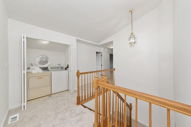 hallway with washer and dryer, light colored carpet, and lofted ceiling