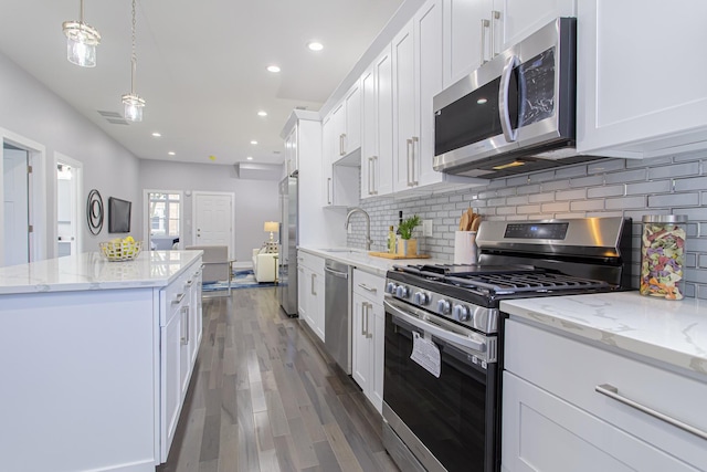 kitchen featuring dark wood-type flooring, hanging light fixtures, sink, appliances with stainless steel finishes, and white cabinetry