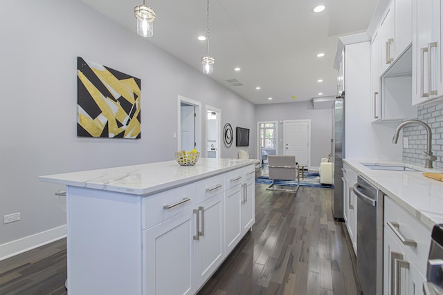 kitchen featuring pendant lighting, a center island, white cabinetry, and sink