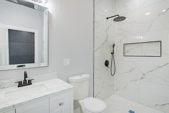 bathroom with tiled shower, vanity, and toilet