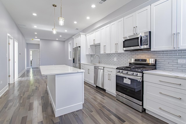 kitchen with a center island, stainless steel appliances, white cabinetry, and hanging light fixtures