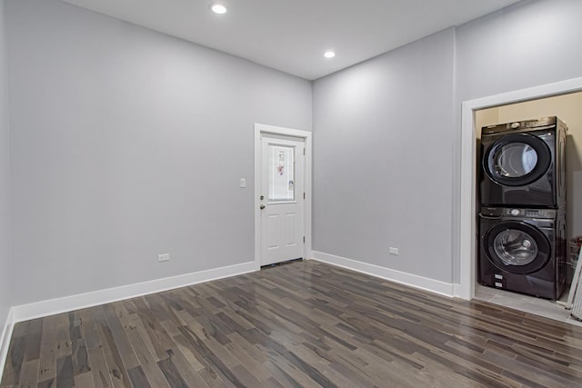 laundry area featuring dark wood-type flooring and stacked washer and clothes dryer