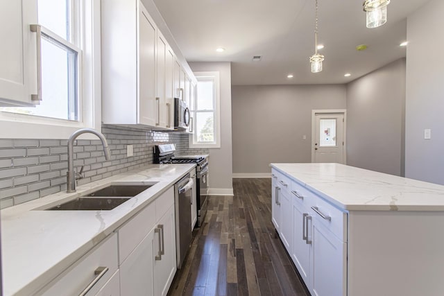 kitchen featuring pendant lighting, dark wood-type flooring, white cabinets, sink, and stainless steel appliances