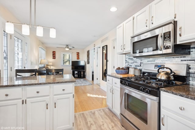 kitchen with backsplash, white cabinets, hanging light fixtures, ceiling fan, and stainless steel appliances