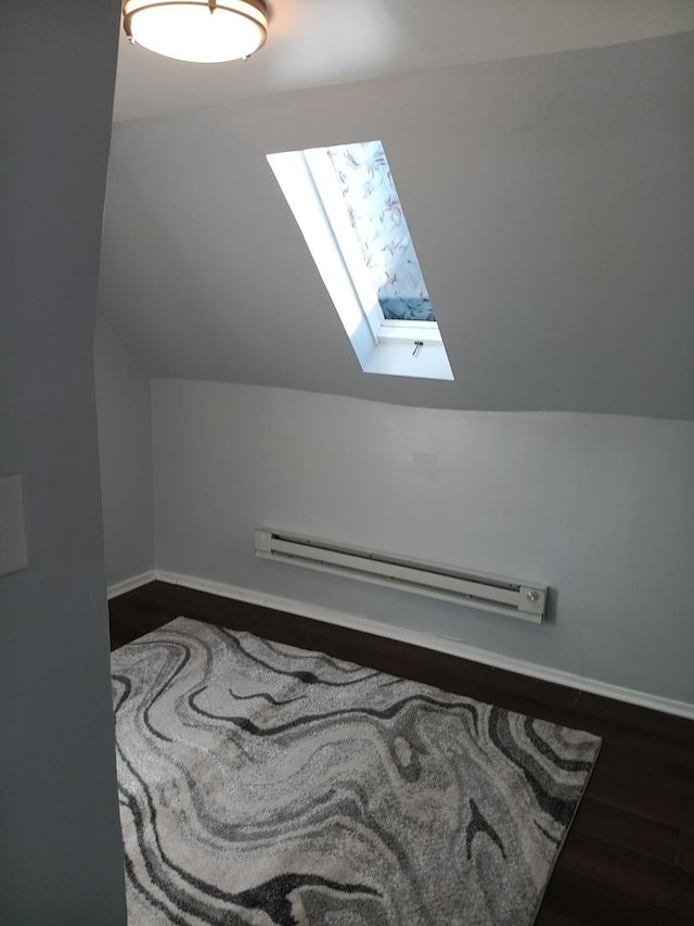 bonus room featuring baseboard heating, lofted ceiling with skylight, and dark wood-type flooring