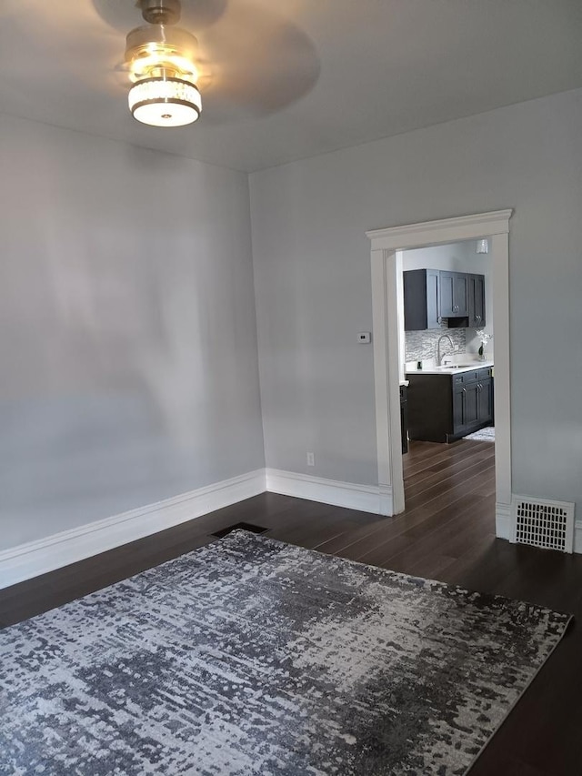 unfurnished room featuring dark hardwood / wood-style floors and sink