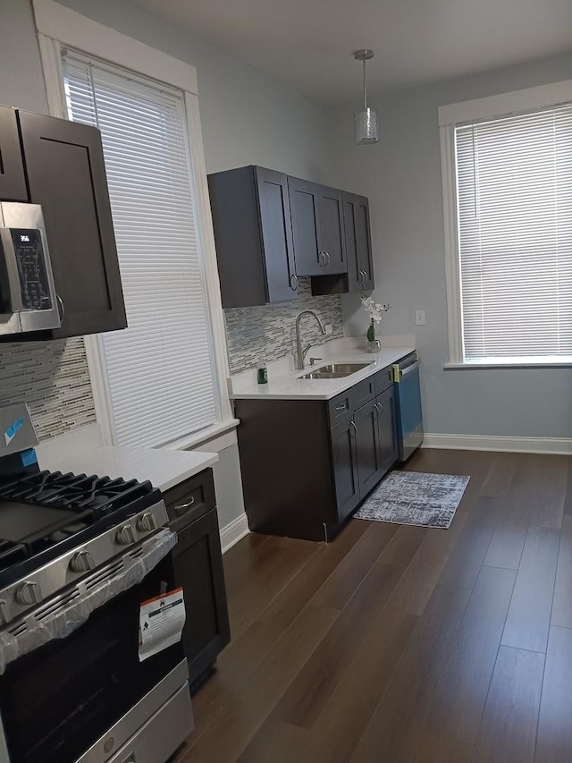 kitchen featuring dark wood-type flooring, sink, tasteful backsplash, decorative light fixtures, and stainless steel appliances