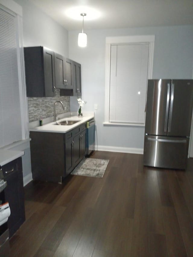 kitchen featuring appliances with stainless steel finishes, backsplash, sink, pendant lighting, and dark hardwood / wood-style floors