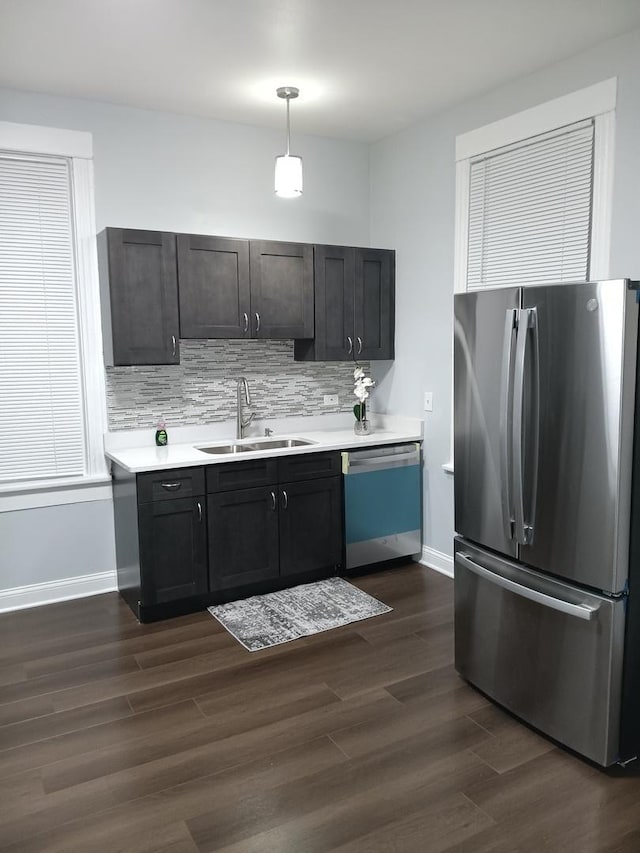 kitchen with sink, dark hardwood / wood-style floors, appliances with stainless steel finishes, tasteful backsplash, and decorative light fixtures