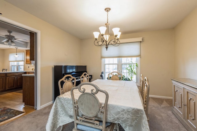 carpeted dining space with ceiling fan with notable chandelier