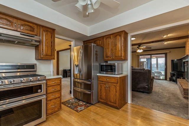 kitchen with beam ceiling, stainless steel appliances, ceiling fan, and light hardwood / wood-style floors