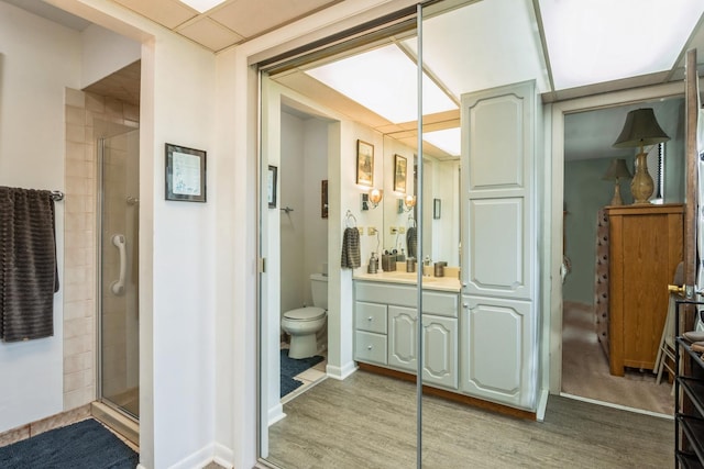 bathroom featuring hardwood / wood-style floors, vanity, toilet, and an enclosed shower