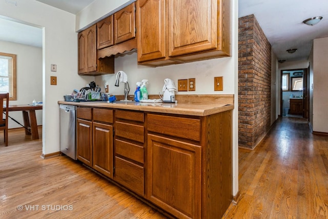 kitchen with sink, stainless steel dishwasher, and light wood-type flooring