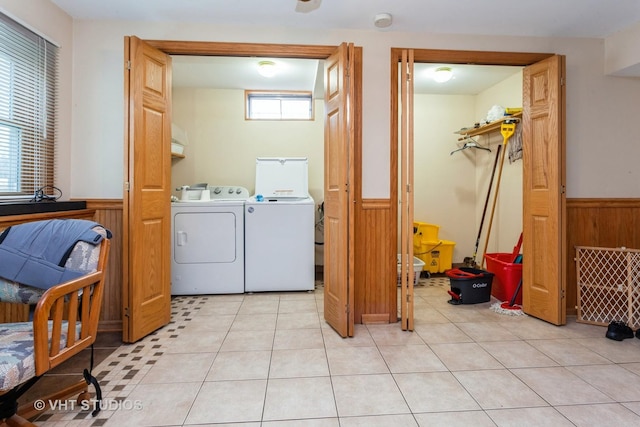 clothes washing area featuring separate washer and dryer, wooden walls, and light tile patterned floors