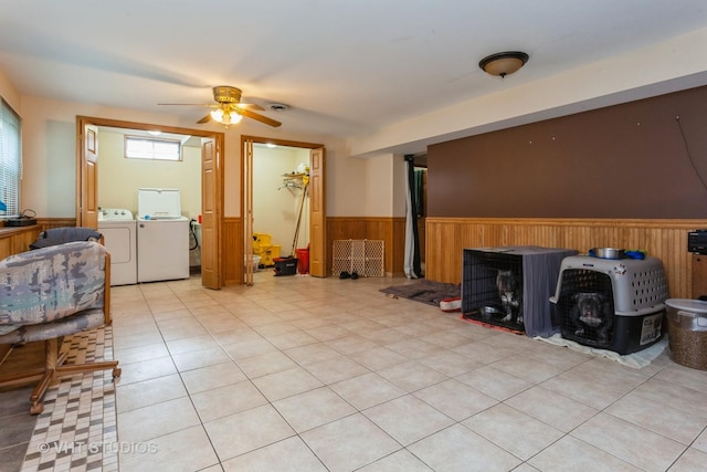 living room with light tile patterned flooring, wooden walls, ceiling fan, and washer and dryer