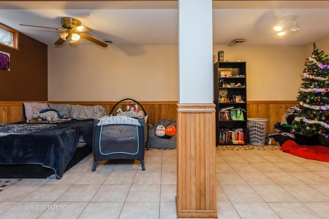 bedroom featuring ceiling fan, light tile patterned floors, and wood walls