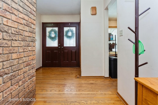 foyer featuring french doors, light hardwood / wood-style floors, and brick wall